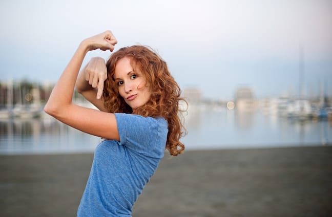 A woman jokingly shows off her muscles on a beach in Marina Del Rey, Calif.